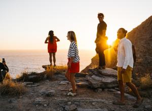 Group of people at cliff edge watching sunset