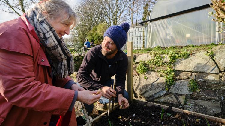 Community member with Eden gardener planting together