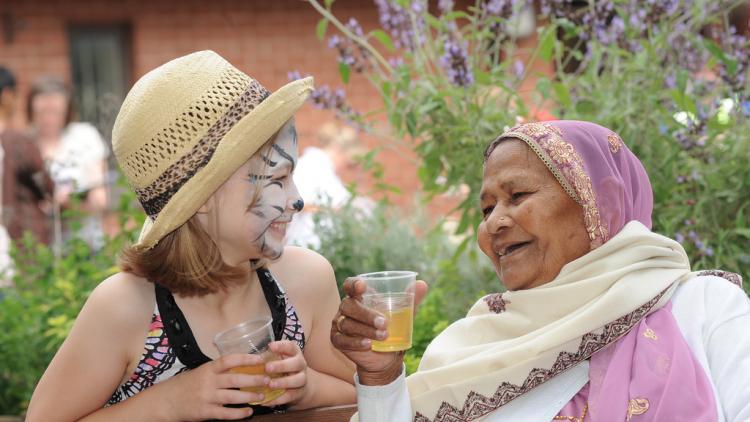 Girl with facepaint and elderly lady enjoying a drink together