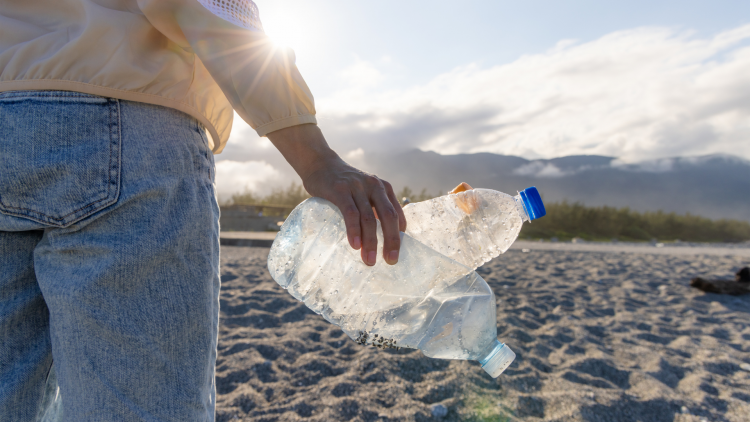 Person holding two empty plastic bottles on the beach