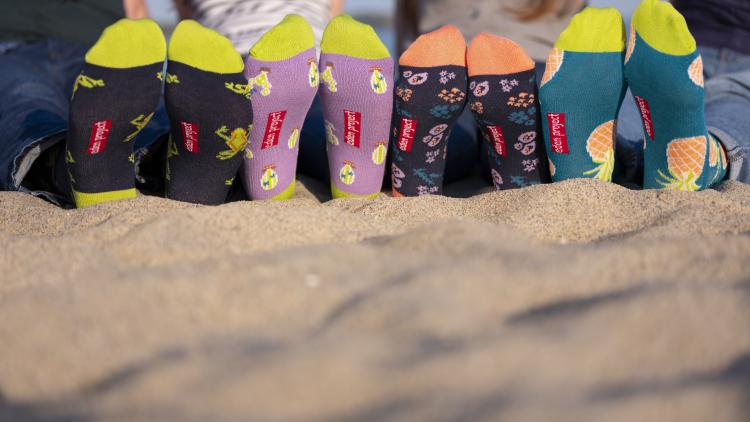 Four people wearing bright Eden Project socks on the beach