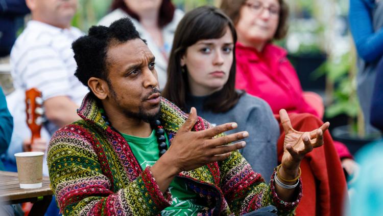 Man discussing ideas with people listening at an Eden Project Community Camp
