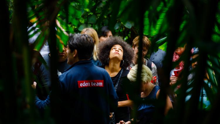 Woman looking up at plants as an Eden team member gives a tour 
