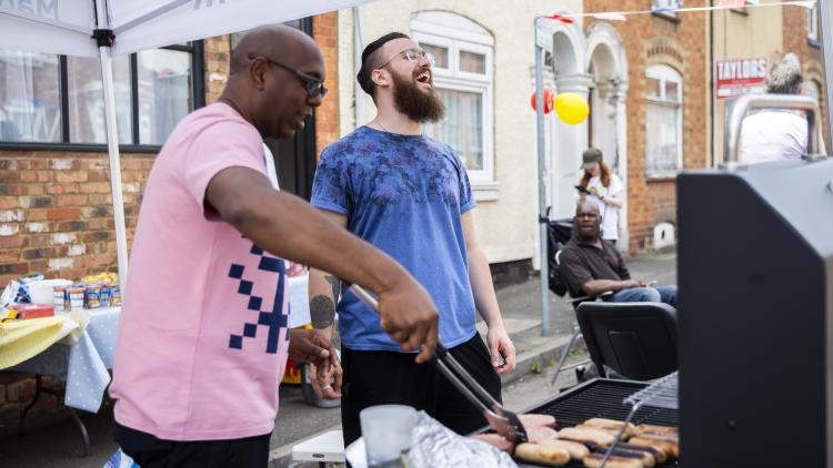 Two men barbecuing at a Big Lunch in their street