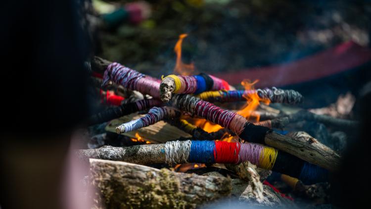 Sticks wrapped in colourful wool burning in a fire