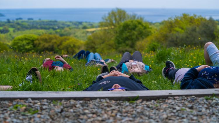 People lying in the grass with the see in the background