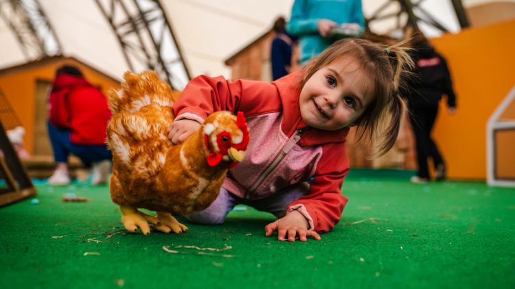 Young girl playing with chicken plush toy