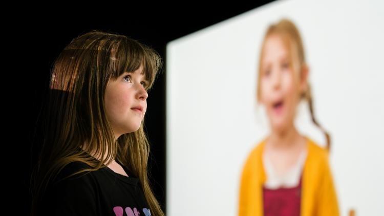 Girl watching film of children talking