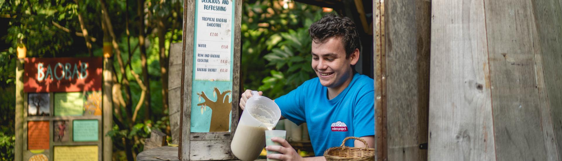 A male Eden Team member pouring a pitcher of drink into a glass at the Baobab & Rum Bar