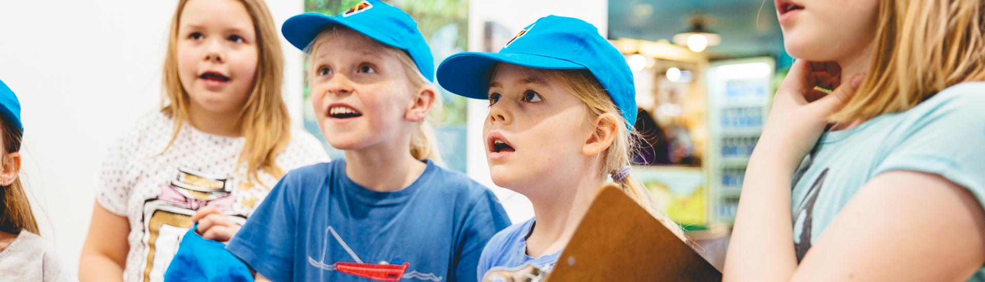 a group of school pupils stood in a line looking at something in front of them in awe