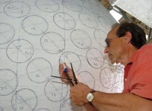 A close up picture of artist Peter Randall-Page working on the Seed sculpture drawing circles where the raised dots would be