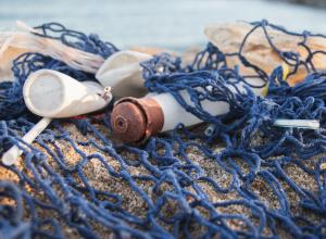 A close up of some plastic on the beach tied in some netting 