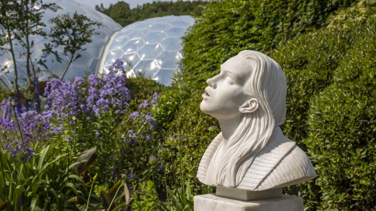 A view of the Ryan Gander water fountain sculpture with the Eden biome's in the background