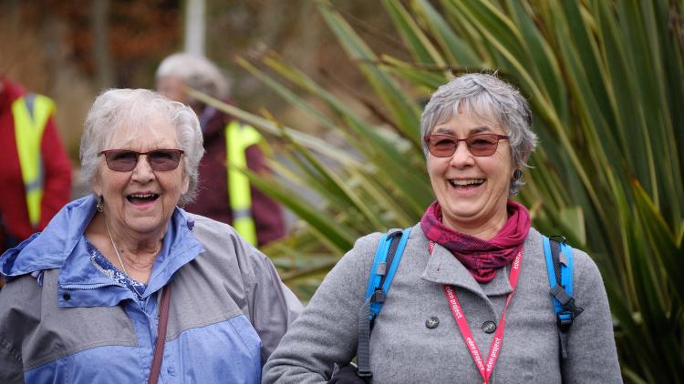 Ladies walking arm in arm in Eden Project's outdoor gardens