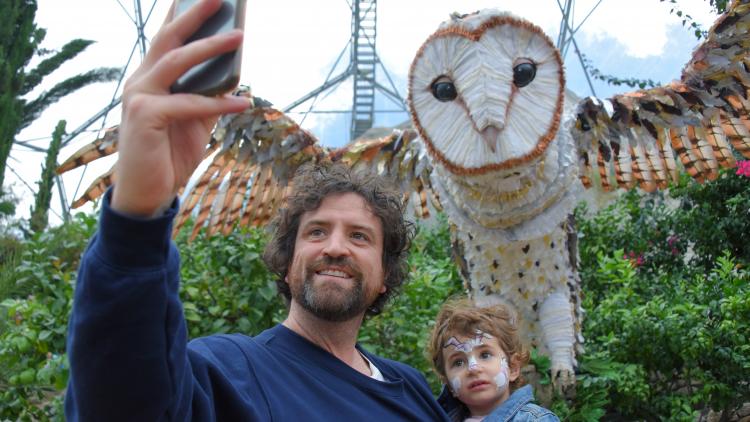 Parent and son taking selfie with giant owl