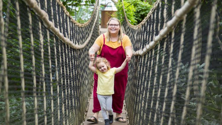 Woman and daughter walking across the bride in the Rainforest