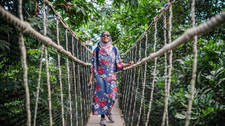 Woman walking across bridge in the Rainforest Biome