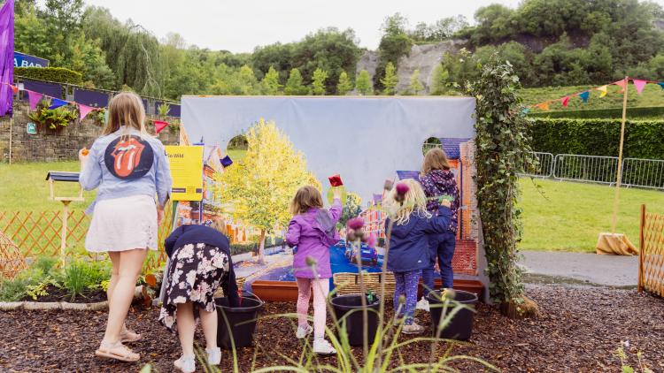 Children playing game throwing bean bags at a wall of holes