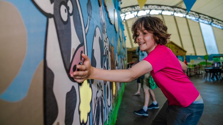 Boy pressing button to stop a cow burp in giant game