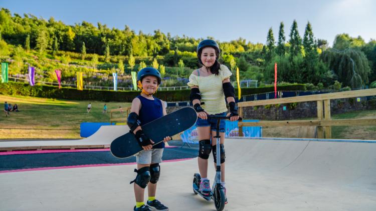 Kids on skate ramp holding skateboard and scooter