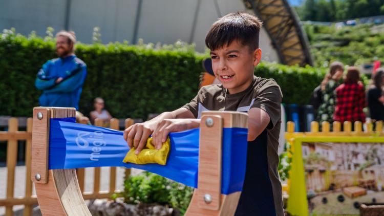 Boy pulling back beanbag in a giant catapult