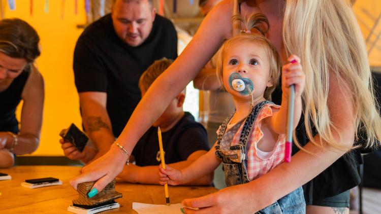 Toddler taking part in a craft activity with the help of her mum
