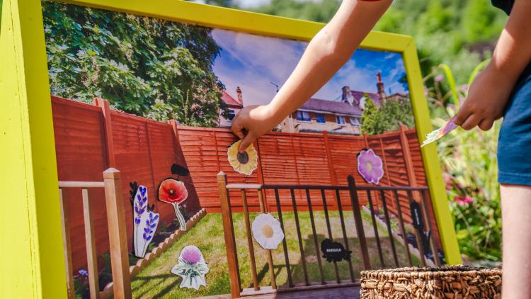 Hand sticking flowers to a garden jigsaw activity