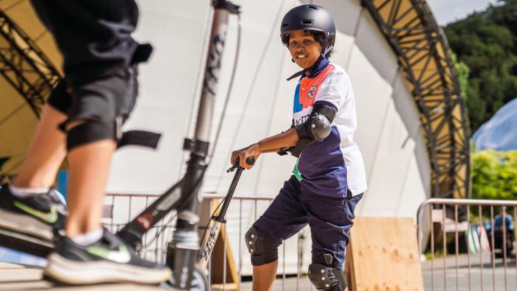 Boy on a skate ramp with a scooter