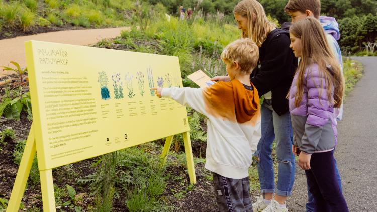 Family looking at Pollinator Pathmaker signage