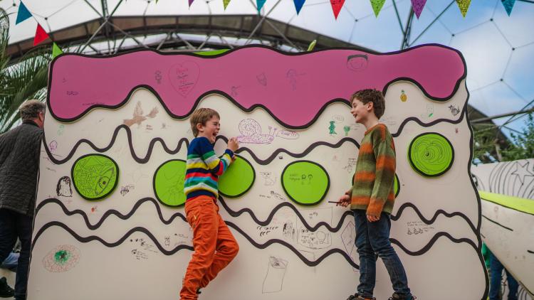 Boys laughing as they draw on giant Tom Gates' inspired cake sculpture