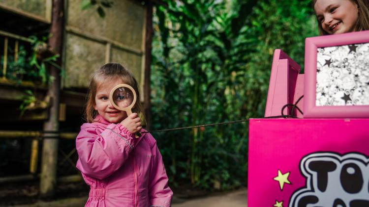 Girl with magnifying glass doing the Tom Gates bug trail in the Rainforest Biome at the Eden Project