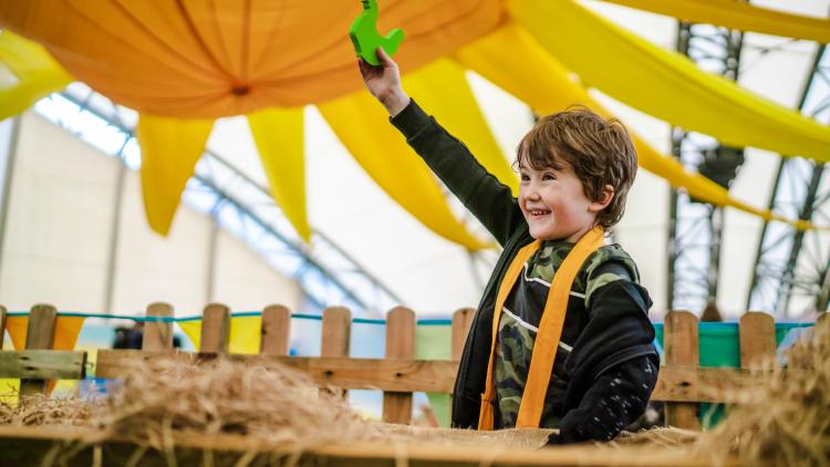 Boy holding up wooden chicken joyfully