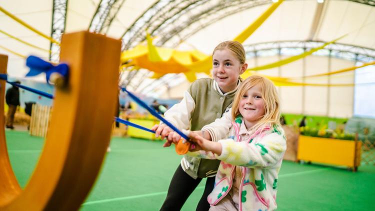 Girls pulling back a giant slingshot