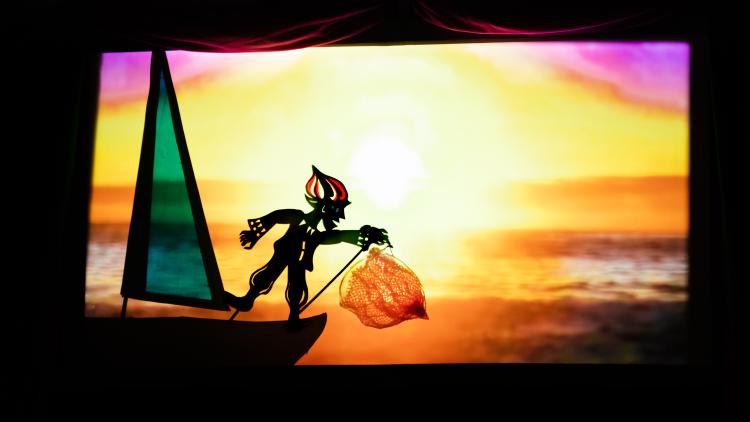 Shadow puppet of a man on a boat with a net