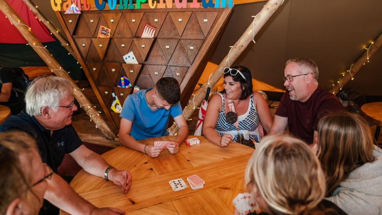 Seven family members sat around a table playing a card game as part of our boardgame compendium 