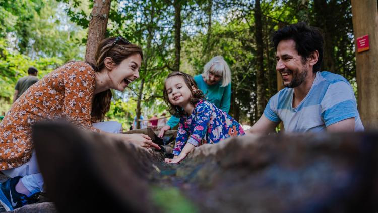 Mother, father and daughter laughing and playing in Babbling Brook, the water course part of our new adventure play area