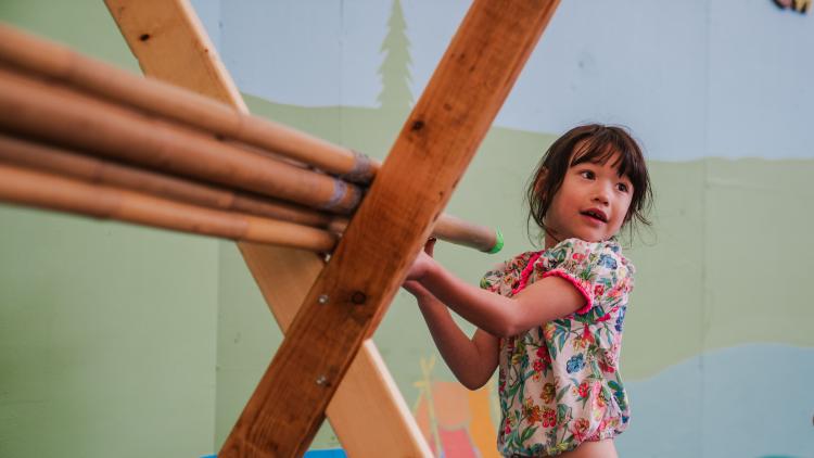 Young child building a den using a wooden structure inside our Arena area, 