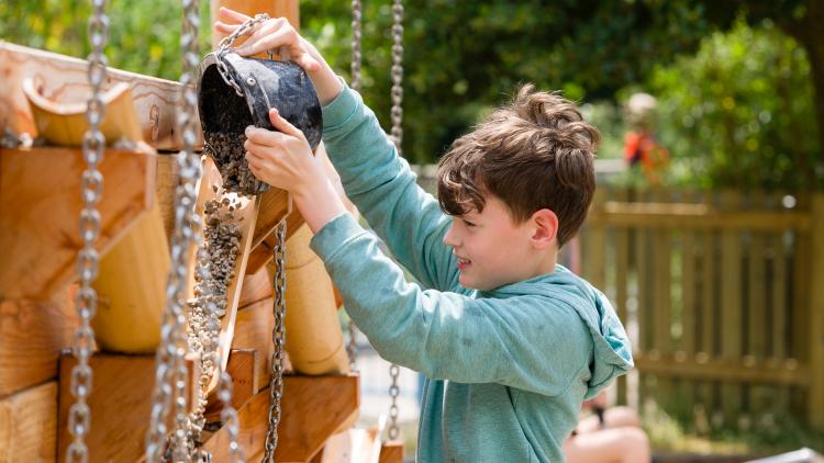 Boy tipping gravel from a bucket into a shoot