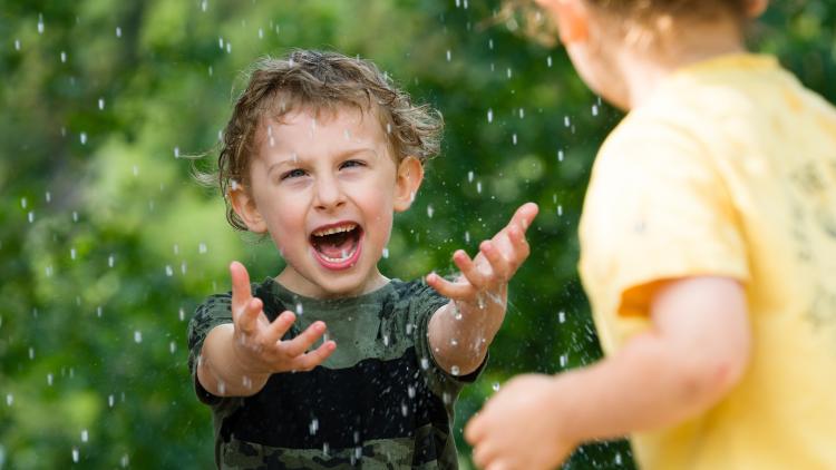 Boy holding his hands out catching drops of water raining down