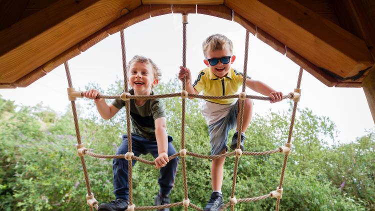 Young boys climbing up rope net