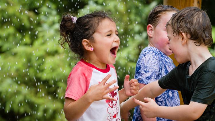 Little girl shouting with joy under water play rain drops