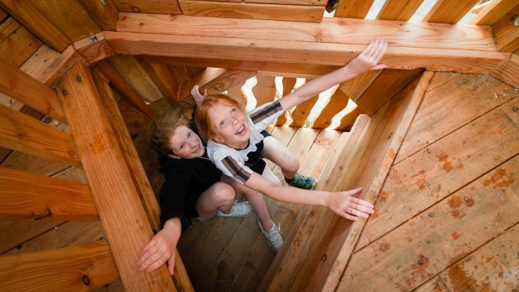 Girls climbing up wooden tower