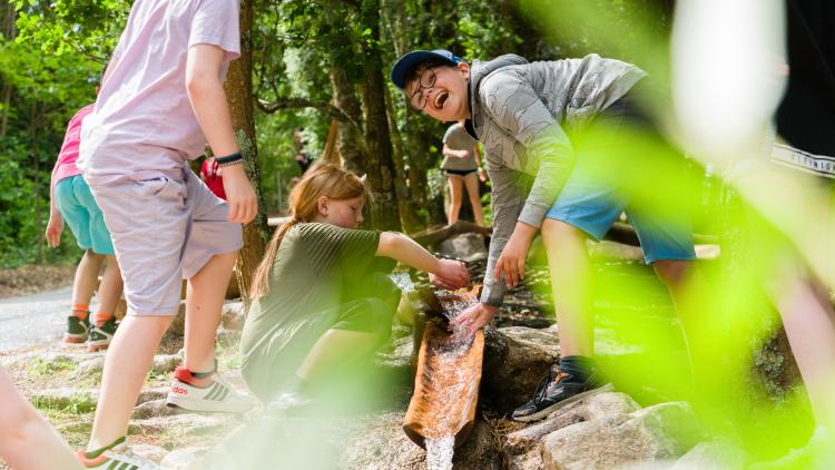 Children playing with water coming down a bamboo water shoot