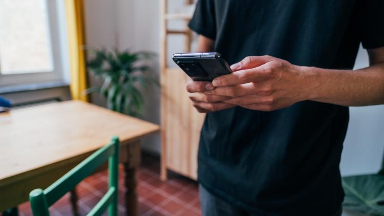 Man's hands using smart phone in a dining room