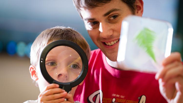 Father and son looking at leaf through magnifying glass