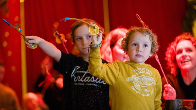 Children with outstretched arms holding wands