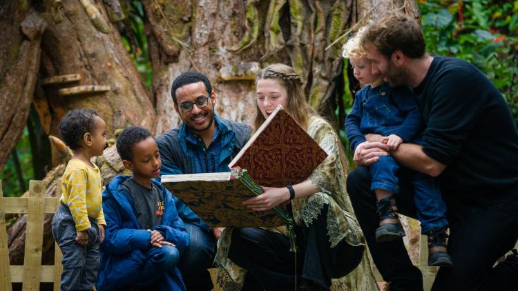 Families reading from a giant ancient book during storytelling