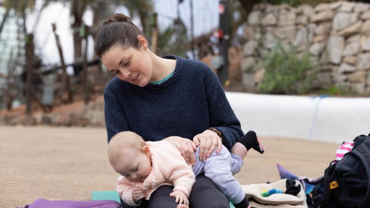 Baby lying on mother's knees during baby yoga session