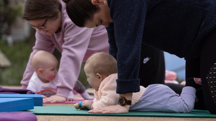 Babies having tummy time on yoga mats with mothers on hands and knees above them
