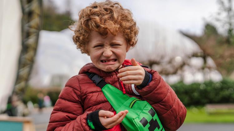 Boy standing outside pulling a face after eating a dried insect